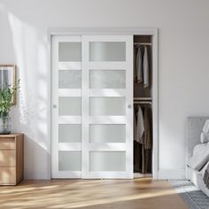 a bedroom with white walls and wooden flooring, an open closet door is shown