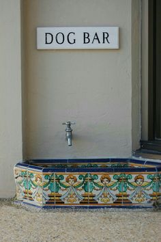 a dog bar sign on the side of a building next to a faucet