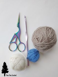 two balls of yarn, scissors and knitting needles on a white surface with pine tree crochet