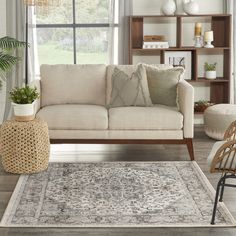 a living room with a couch, chair and rug on the floor in front of a window