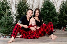 a man and woman are sitting on the floor with christmas trees in front of them