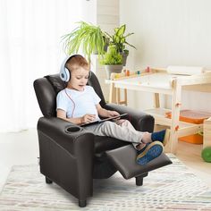 a little boy sitting in a chair with headphones on and looking at a tablet