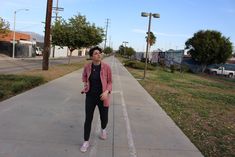 a woman is standing on the sidewalk with her skateboard in hand and looking at the camera