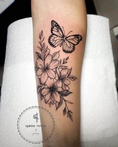 a woman's leg with flowers and butterflies tattoo on the side of her arm