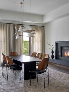 a dining room table with chairs and a fire place in the fireplace behind it is an elegant chandelier