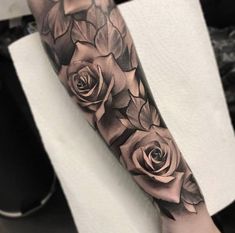 a woman's arm with black and grey roses tattooed on the left side of her arm