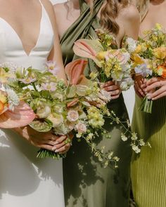 three bridesmaids holding bouquets of flowers in their hands