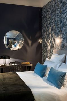 a large bed sitting under a round mirror on the wall above it's headboard