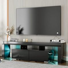 an entertainment center with a flat screen tv mounted on it's side, in front of a striped wall