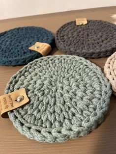 three crocheted round cushions sitting on top of a wooden table