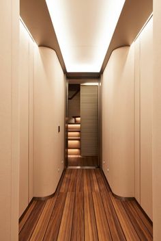 an empty hallway with wooden flooring and white walls, leading to the closets