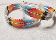 two bracelets made out of multicolored seed beads on a white tablecloth