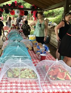 several people standing around a table covered in plastic containers with food on top of it