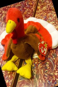 a stuffed turkey sitting on top of a wooden table next to a red and white pillow