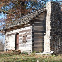 an old log cabin sitting in the grass