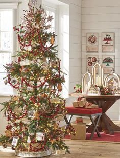 a decorated christmas tree in the corner of a living room with red and gold ornaments