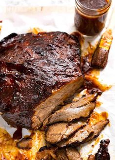 a large piece of meat sitting on top of a table next to some sauces