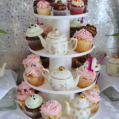 a three tiered cake stand with cupcakes and teapots on it