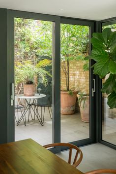 an open patio door leading to a dining room with potted plants on the table