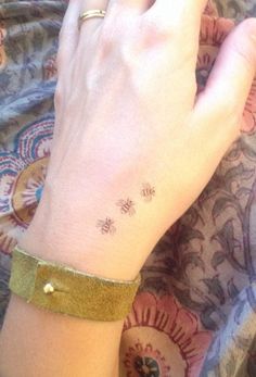 a woman's hand with a small tattoo on her left wrist and the word bee