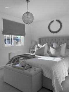 a bedroom with a bed, ottoman and chandelier in black and white colors