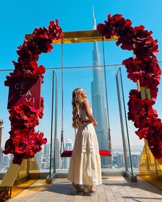 a woman standing in front of a red flower arch