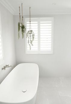 a white bath tub sitting in a bathroom next to a window with shutters on it