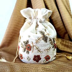 "The sweetest potli bag to enhance any outfit! Hand embroidered with red and orange metallic flowers on luxurious cream white velvet and embellished with genuine semi precious stones to create an opulent effect. It is certain to bring you compliments. Perfect for Indian wedding! Expertly hand embroidered by third generation master zardozi artisans. Of heirloom quality. - Measures approx 9\" tall, base is 6\" across. - Useable interior space is 6 x 6\". - Rigid bottom and 2 inch sides ensures you Beaded Pouch Bag, Beaded Pouch, Zardozi Embroidery, Potli Bag, Pumpkin Patch Outfit, Wrist Bag, Wedding Handbag, Embroidered Handbag, Potli Bags