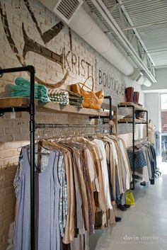 clothes are on racks in front of a brick wall