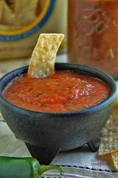 a black bowl filled with salsa and tortilla chips on top of a table