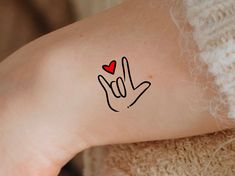 a woman's arm with the word love written on it and a red heart in her hand