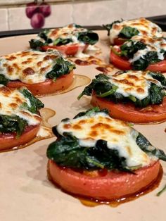 tomatoes and spinach topped with cheese on top of a baking sheet