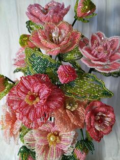 some pink flowers with green leaves and beads