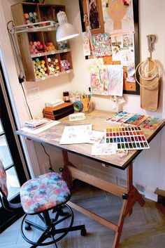 a desk with some art supplies on it and a chair in front of the desk