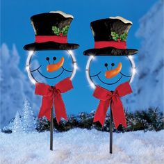 two snowmen wearing hats and scarfs in the snow