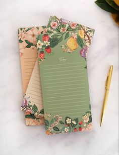 three notepads with flowers on them next to a pen and flower potted plant