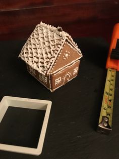 a ginger house next to a measuring tape, and a cookie shaped like a house