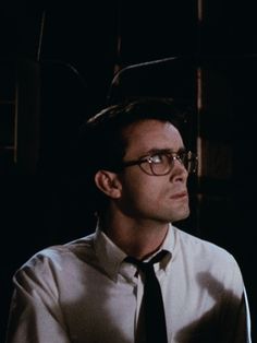 a man wearing glasses and a tie in the dark