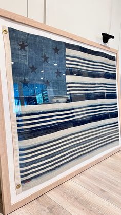 an american flag is displayed in front of a wooden frame on the floor with other items around it