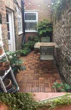 an outdoor patio with potted plants on the side and a table in the middle