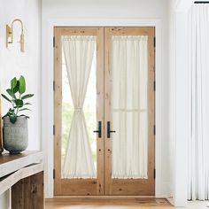 a white room with two doors and a potted plant on the table next to it