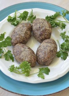 four meatballs on a plate with parsley