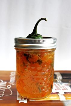 a jar filled with pickles sitting on top of a table next to a book