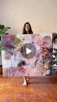 a woman standing in front of a large painting on top of a hard wood floor