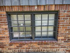 a brick building with two windows and bars on the window sill, in front of it