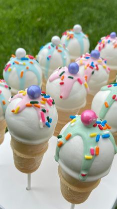 several ice cream cones with sprinkles on them sitting on a white table