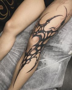 a woman's leg with black ink on it and an abstract design in the middle