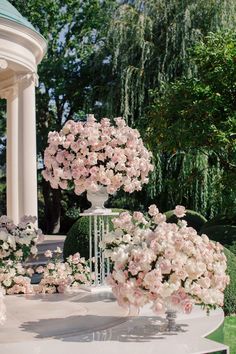 there are many pink flowers on the table in the garden and one is surrounded by greenery