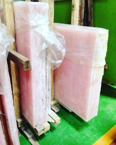 two pink blocks are wrapped in plastic and sitting on pallets next to each other