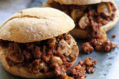 two sloppy joe sandwiches sitting on top of a cutting board